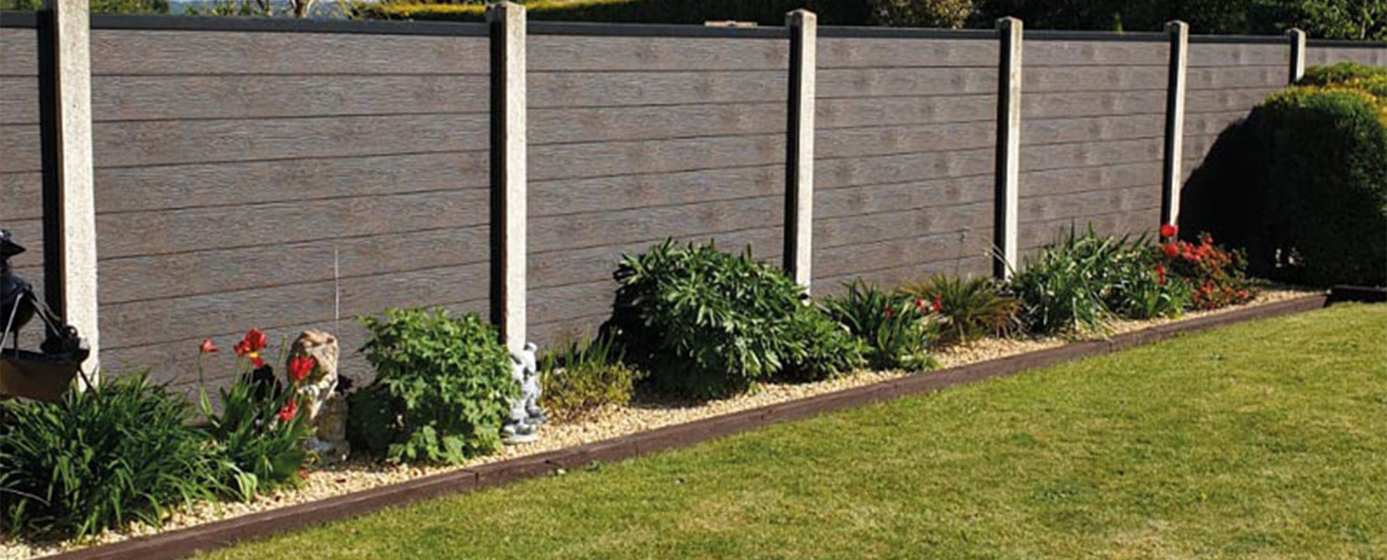 Planted border in front of a panel fence with concrete posts